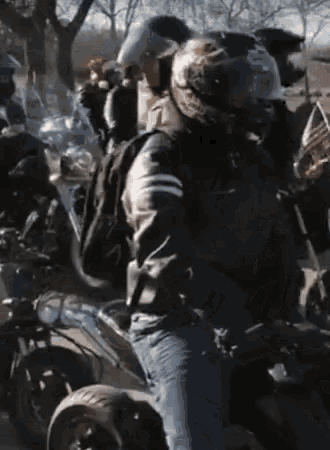 a man wearing a helmet is riding a motorcycle in a crowd