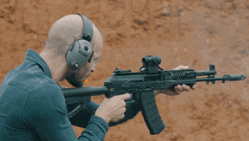 a man wearing headphones is holding a rifle in his hands .