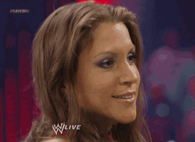 a woman is making a funny face in front of a sign that says w live