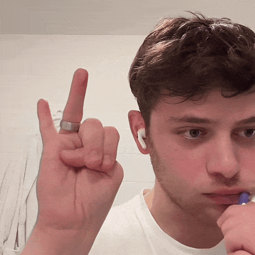 a young man with a ring on his finger is making a horn sign