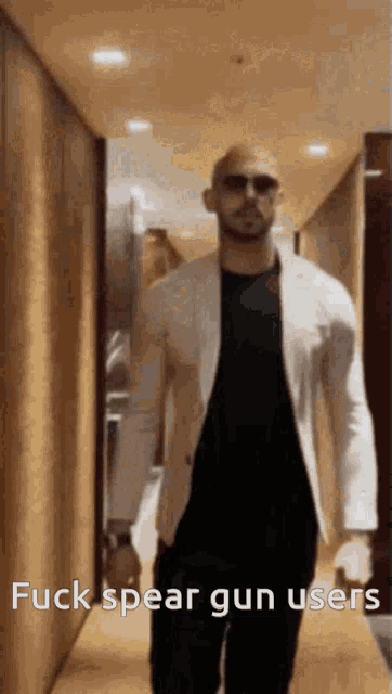 a man in a white jacket is walking down a hallway with the words fuck spear gun users written on the bottom
