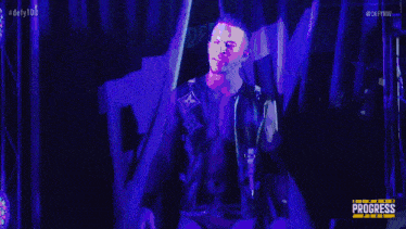 a man without a shirt is standing in a dark room in front of a blue background .