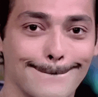 a close up of a man 's face with a fake mustache making a funny face .