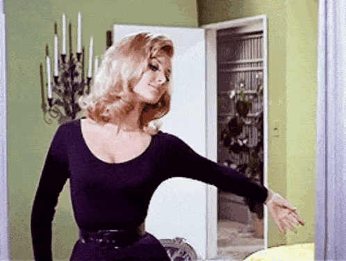 a woman in a black dress is standing in a living room .