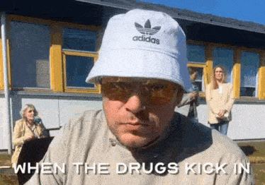 a man wearing a white adidas hat and sunglasses .