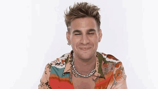 a man wearing a colorful shirt and a chain around his neck
