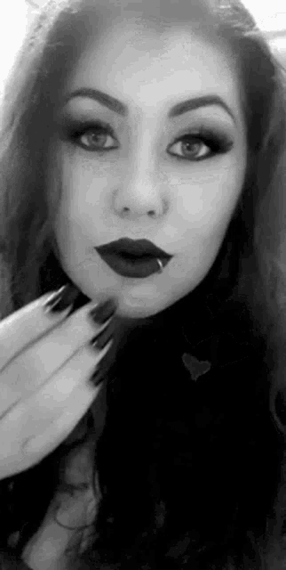 a black and white photo of a woman with red lipstick and a piercing in her lip .