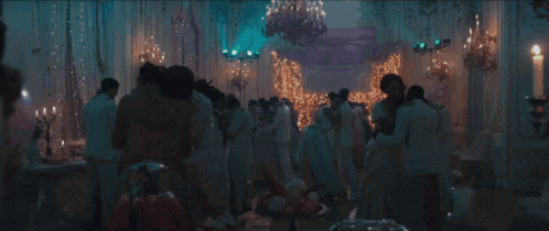 a crowd of people are dancing in a ballroom with candles