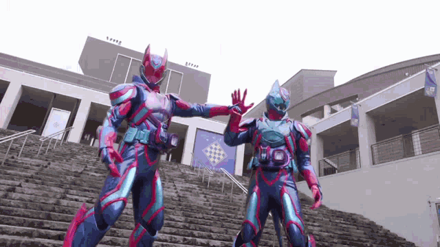 two superhero figures are giving each other a high five while standing on a set of stairs .