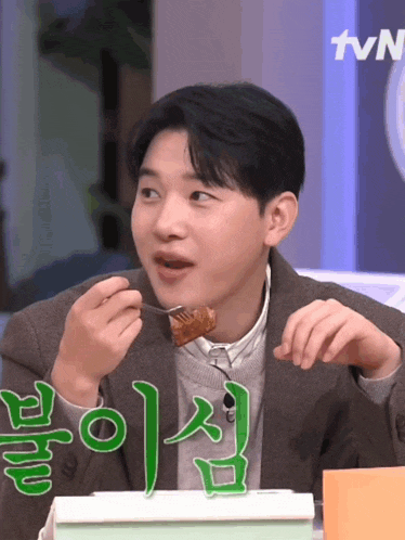 a man is eating a piece of food with a tvn logo behind him