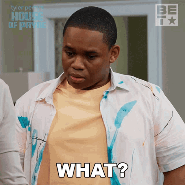 a man wearing a shirt that has blue paint on it says " what "