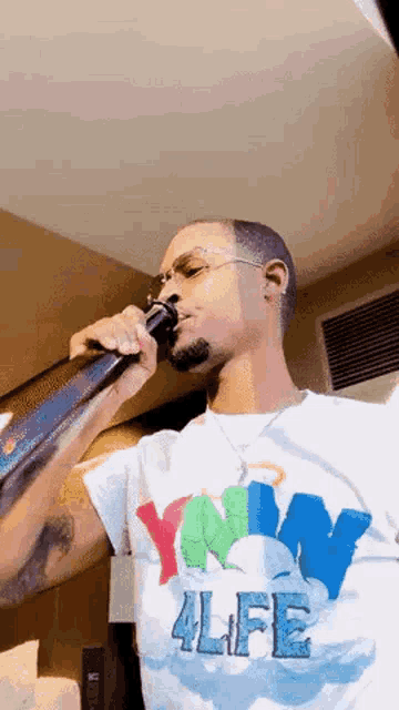a man is singing into a microphone while wearing a t-shirt that says `` 4life '' .
