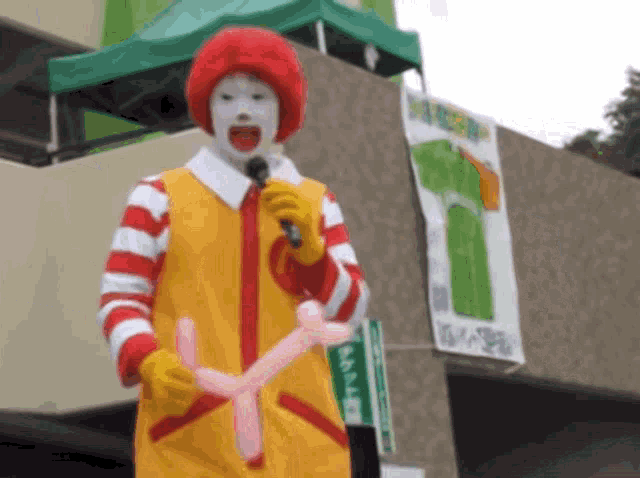 a mcdonald 's clown is holding a microphone and balloons