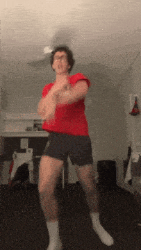 a man in a red shirt and blue shorts is jumping in the air