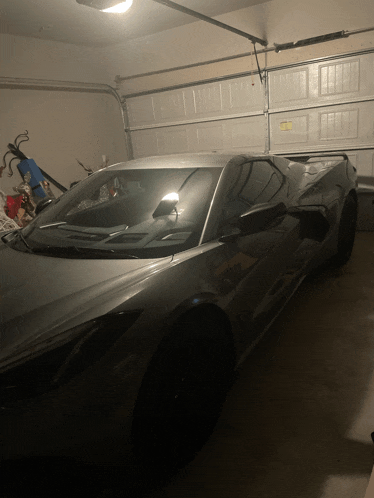 a silver sports car is parked in a garage with a garage door open