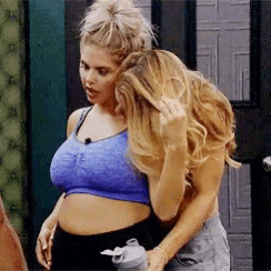 two women are hugging each other in a room . one of the women is pregnant .