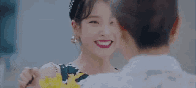 a woman is smiling while holding a bouquet of flowers and looking at another woman .