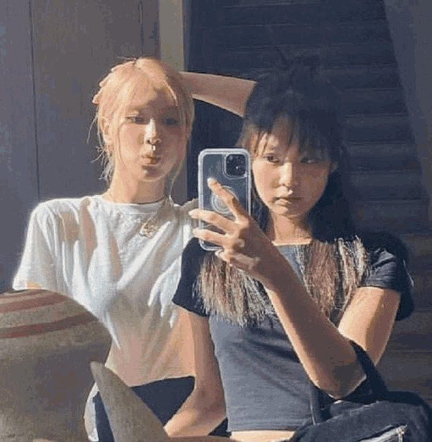 two girls are taking a selfie in the mirror .
