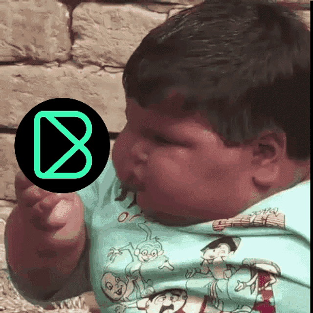a baby in a blue shirt with a green circle with the letter b in it