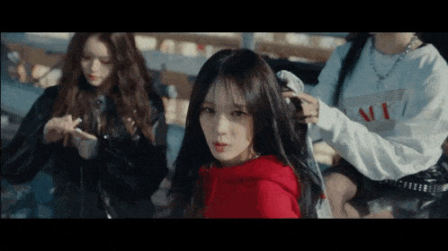 a girl in a red hoodie is looking at the camera while two other girls look on .
