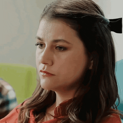 a woman with a black bow in her hair looks to the side