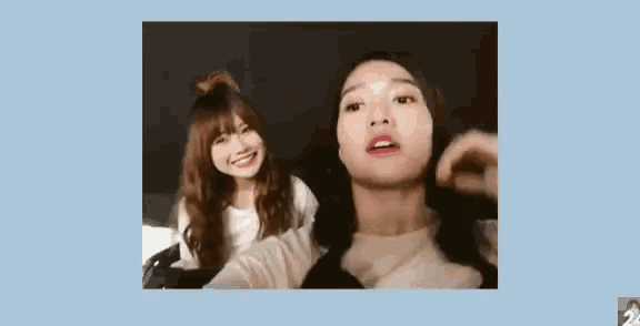a couple of women are standing next to each other and one of them is touching the face of the other .
