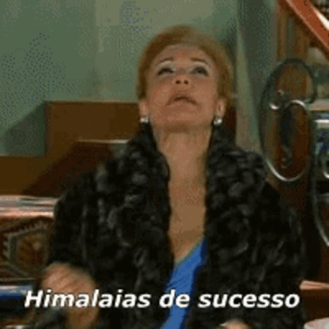 a woman in a fur coat is sitting on a staircase with the words himalaias de sucesso written below her .