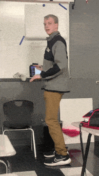 a man standing in front of a white board that says ' economics '