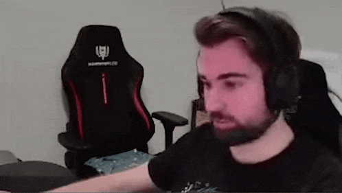 a man with a beard wearing headphones is sitting in front of a computer .