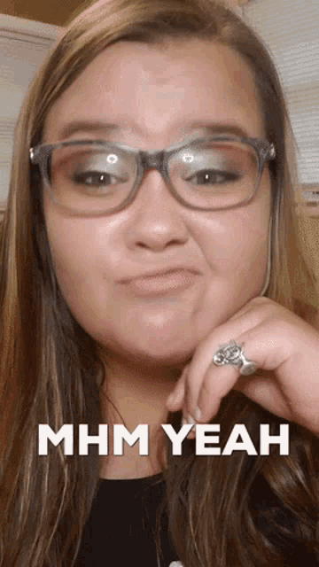a woman wearing glasses and a ring has the words mhm yeah written on her face