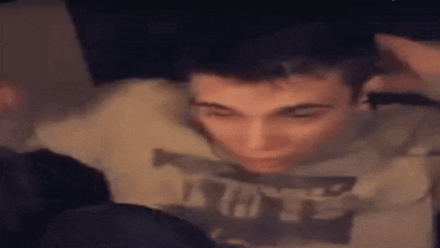a man wearing a sweatshirt with the word nuts on it is sitting in a dark room with other people .