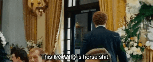 a man in a suit is standing in front of a group of people and talking about horse shit .