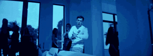 a man is standing in a room with a group of people behind him