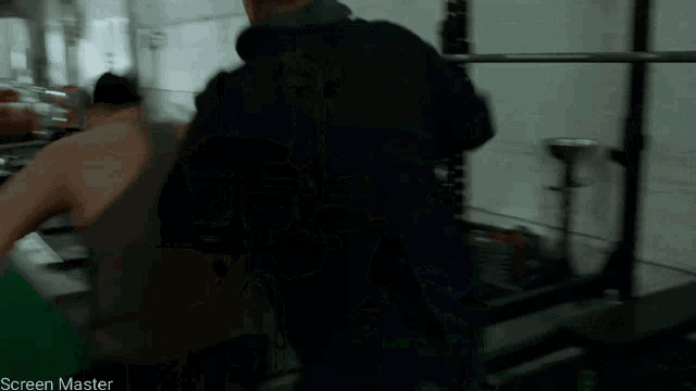 a man in a black jacket is lifting a barbell in a dark room with a screen master watermark