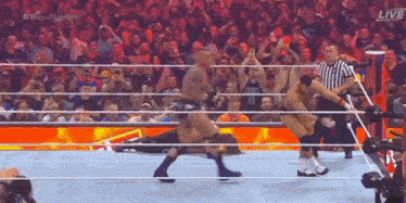 a group of men are wrestling in a ring with a referee .
