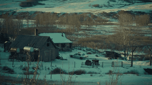 a snowy landscape with a police car parked in front of a house