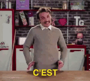 a man with a mustache is standing in front of a table with the word c ' est on it