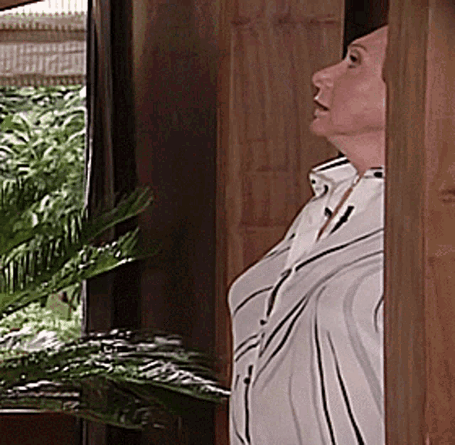 a woman in a striped shirt is standing in a doorway looking out a window