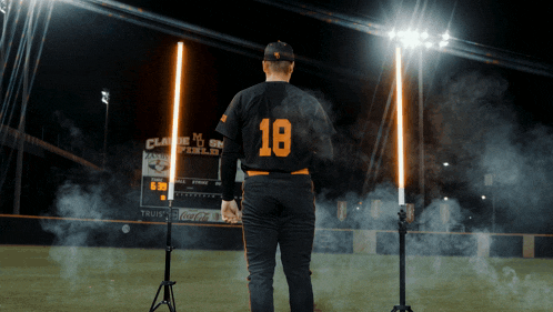 a baseball player with the number 18 on his jersey stands on the field