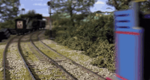 a blurry picture of a train going down the tracks with trees in the background