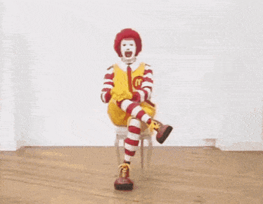 a mcdonald 's clown is sitting in a chair with his leg up