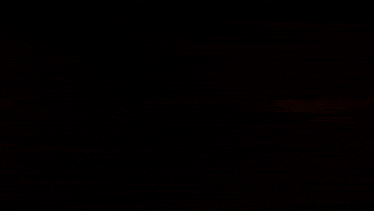 a blurred image of a person holding a gun in a dark room with a red light behind them