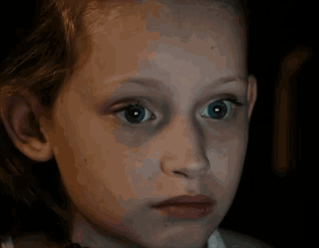 a young girl with blue eyes looks at the camera