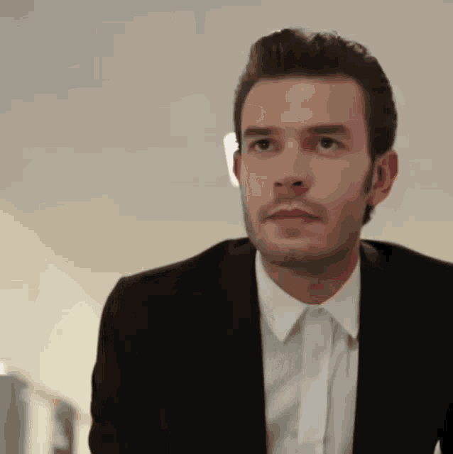a man in a suit and white shirt is looking to the side