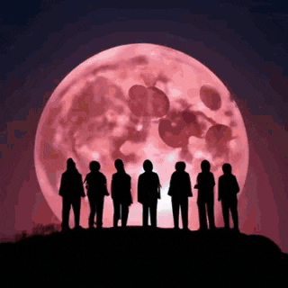 a group of people standing in front of a full moon