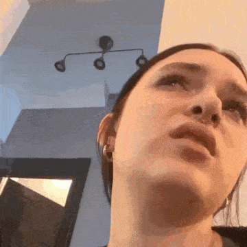 a woman with a nose ring is looking up at the camera in a room .
