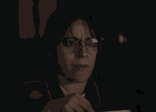 a woman wearing glasses and a denim jacket is sitting in front of a computer screen .