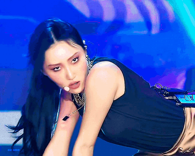 a woman in a black tank top is kneeling down with a microphone