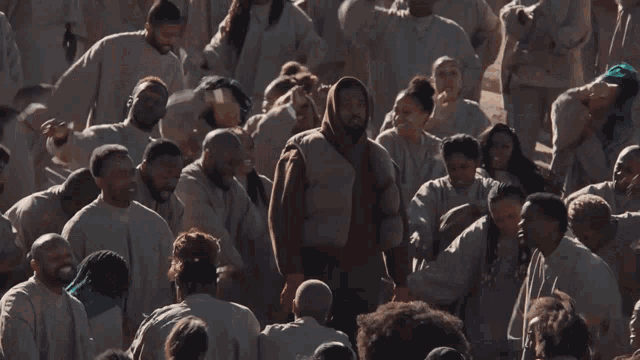 a man in a brown hoodie is surrounded by a large group of people