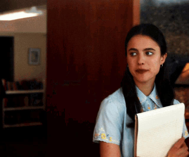 a woman in a blue shirt is holding a folder that says ' i 'm sorry ' on it